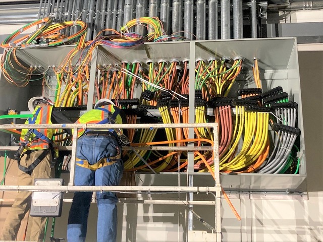 Electrician pulling wires through a junction box.